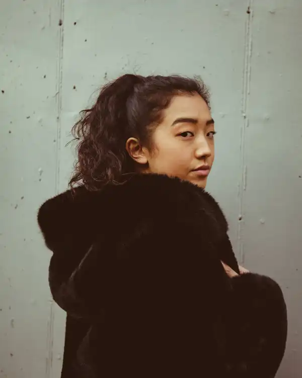 A woman wearing a black faux-fur coat with a hood